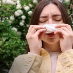 a woman with blocked nose and bottle of anu taila